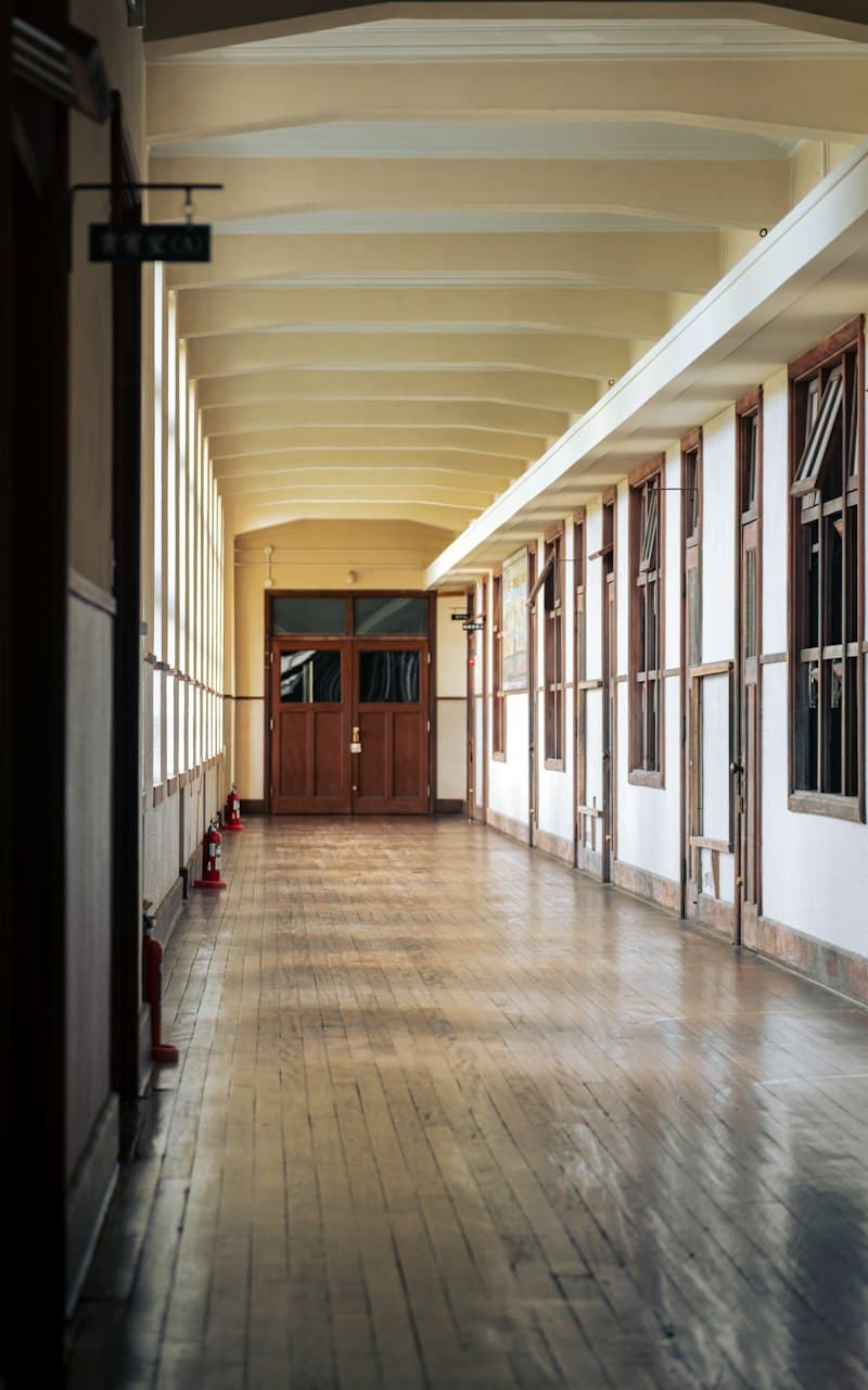 A long, bright school corridor with a wooden floor and tall windows