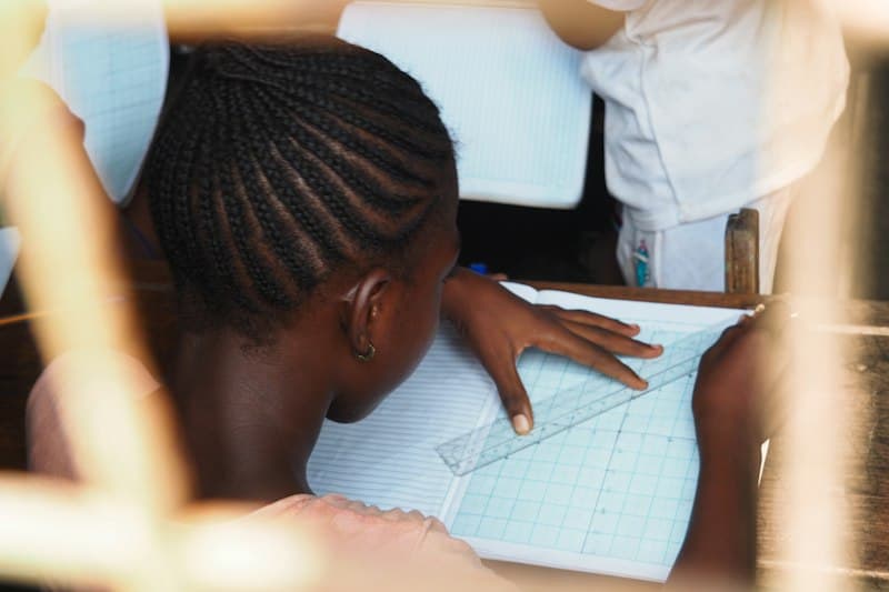 A student drawing careful lines with a ruler in an exercise book