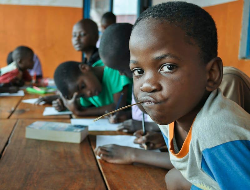 A pupil looking up from his desk while classmates write