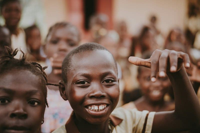 A group of smiling pupils, one pointing towards the camera