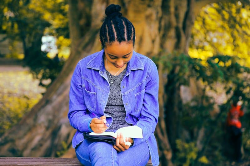 A senior student reading and taking notes under a tree