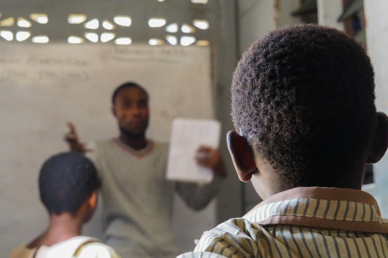 A teacher holding up a sheet of paper while students listen